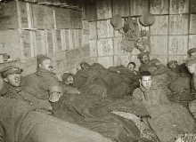 Frost-bitten soldiers lying on straw in shelters constructed of biscuit boxes at a store dump at Suvla, after the frost at the end of November 1915.